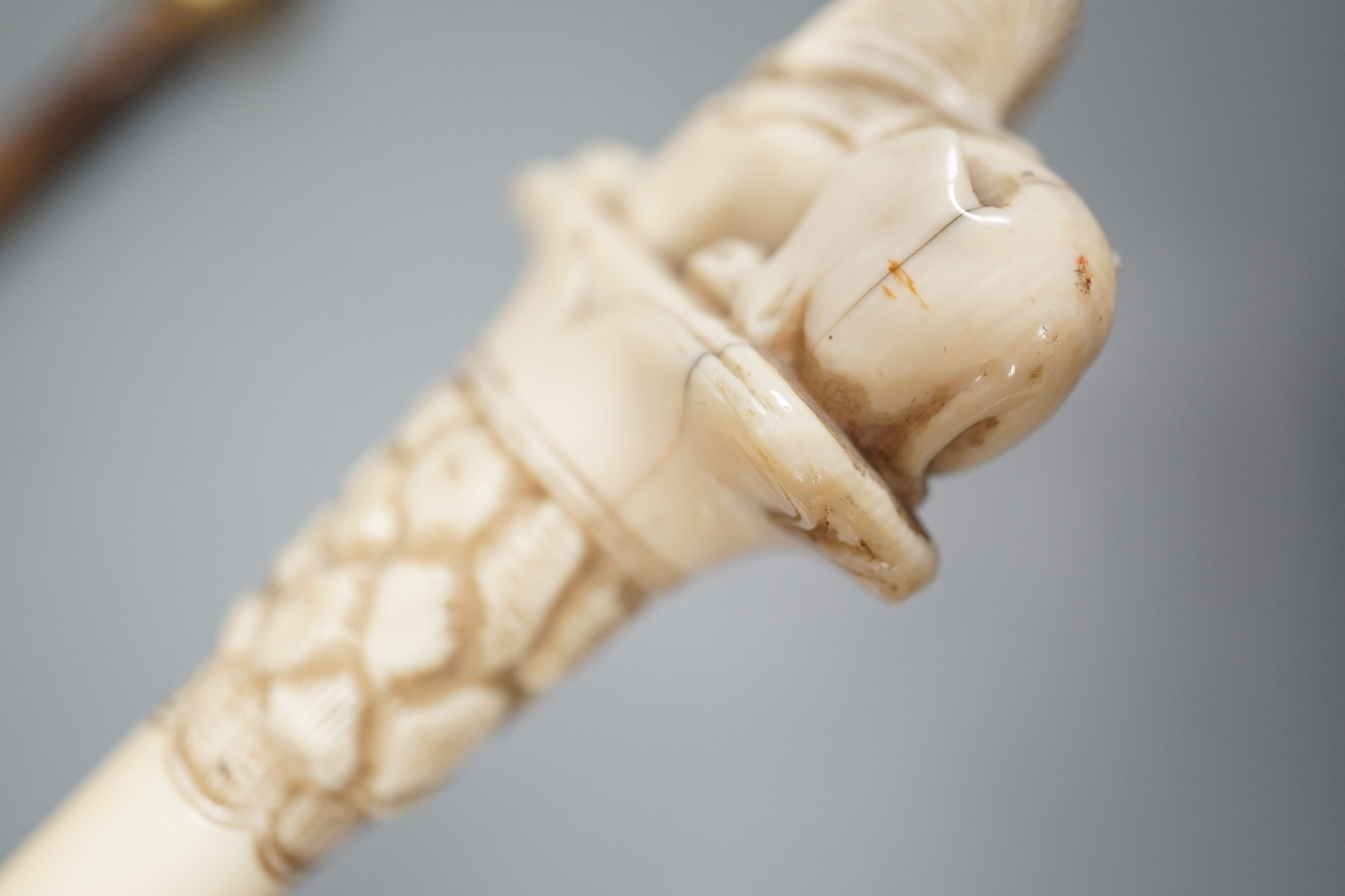 An early 20th century ivory ‘sphinx’ parasol handle, 84cm, together with another gold and iron damascened parasol handle, 62cm